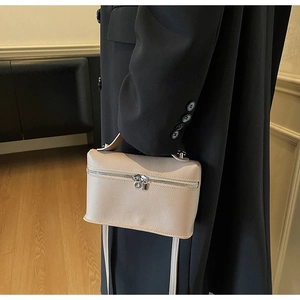 Detail view of beige lychee texture leather handbag with dual-zipper and metallic padlock
