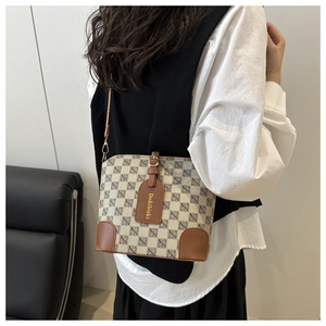 Detail view of beige crossbody shell bag with geometric patterns and brown leather accents