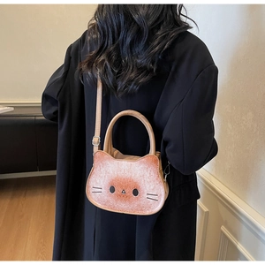 Detail view of a cat-shaped toast crossbody bag worn over a black blazer for style