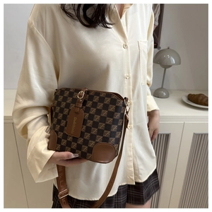 Brown checkered crossbody bucket bag shown on a model in a minimal indoor setting