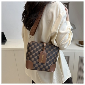 Retro plaid bucket bag with leather accents and wide fabric strap shown on a model