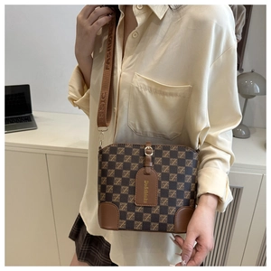 Brown checkered bucket bag with branded wide strap shown on model in modern office setting