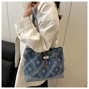 Détail du sac cabas en jean à motif étoiles, franges et pendentif cerf doré