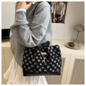 Detail of tweed bucket bag featuring black and white checkered pattern and gold deer charm