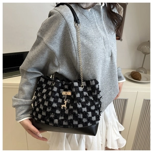 Close-up of checkerboard tweed shoulder bag with gold chain strap and deer charm