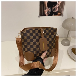 Detail of vintage bucket bag with plaid canvas, leather corners, and woven logo shoulder strap