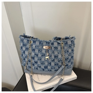 Detail of blue denim tote bag with frayed edges and golden deer charm on buckle