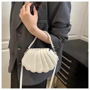 Détail du sac à main blanc en forme de coquille avec anse en perles et cuir texturé
