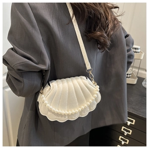 Détail du sac coquillage blanc avec chaîne de perles et garniture dorée sur blazer gris