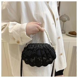 Détail du sac coquille noir avec poignée en perles et texture cuir serpent plissée