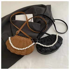Détail de sacs en forme de coquillage noirs et marrons avec texture serpent et perles