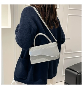 Gros plan du sac à paillettes argentées avec rabat ondulé et poignée métallique