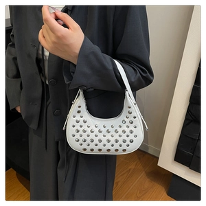 Dettaglio borsa hobo bianca con borchie d'argento indossata da modella con blazer grigio