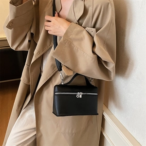 Elegant black lychee leather vanity bag with silver zippers and top handle on model