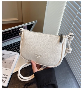 Close-up of white litchi grain leather crossbody bag with dark metallic zipper detail