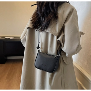 Detail of black pebbled leather crossbody bag with HUAQI logo and knotted shoulder strap