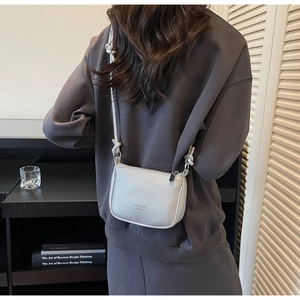 Detail view of silver lychee grain leather crossbody bag showing shoulder strap knot
