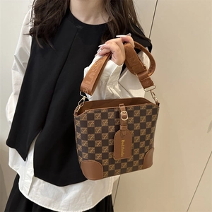 Brown checkered bucket bag with wide CLASS strap shown by a model for a vintage look