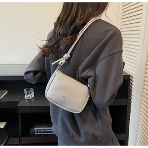 Silver lychee pattern shoulder bag shown on model in a minimalist home setting