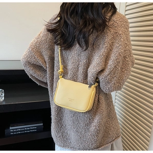 Detail of yellow pebbled leather crossbody bag with silver zipper and slim strap