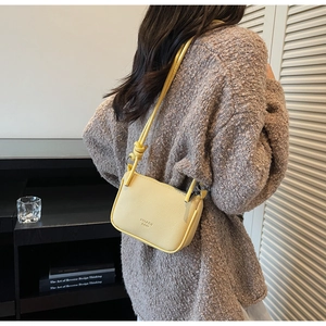 Close-up of yellow pebbled leather shoulder bag with zipper and logo detail
