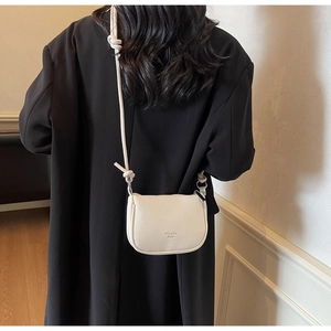 Detailed back view of a woman wearing a white litchi pattern mini crossbody phone bag