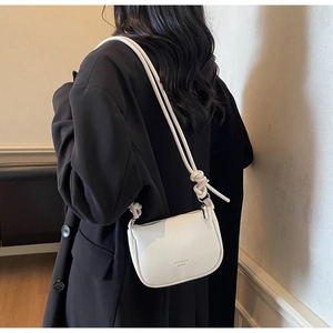 Detail view of a white pebble leather crossbody bag with decorative knotted strap details
