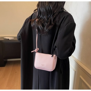 Detail of pink lychee grain leather crossbody bag with a slim strap and zipper closure