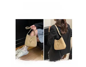 Détail du sac sous l'aisselle en PU beige avec boucle dorée et gland décoratif