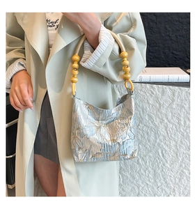 Detail of floral jacquard tote bag with rope handles and wooden bead accents