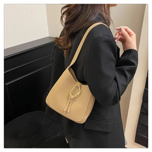Gros plan d'un sac à bandoulière en cuir beige avec une boucle décorative dorée unique