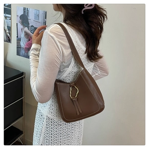 Détail du sac à bandoulière en cuir marron foncé avec coutures blanches et anneau doré