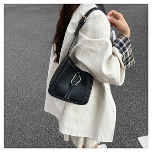Détail du sac seau noir avec surpiqûres blanches et fermoir en métal doré élégant