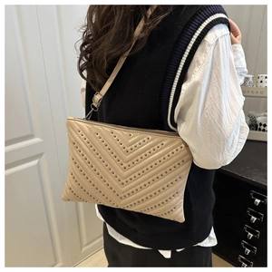 Detail of beige underarm bag with black V-shaped rivets on a vintage crossbody bag