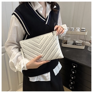 Close-up of white V-quilted faux leather clutch with metallic studs and wrist strap