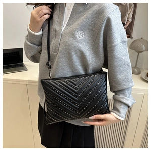 Detail of black chevron quilted shoulder bag with silver rivet studs and zip closure