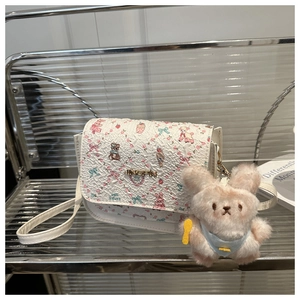 Detail of white cartoon bear print crossbody bag with cute pink plush bunny charm