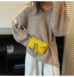 Detail of yellow leather crossbody bag featuring a unique silver character zipper pull