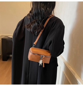 Orange mini leather crossbody bag on black suit jacket showing adjustable shoulder strap