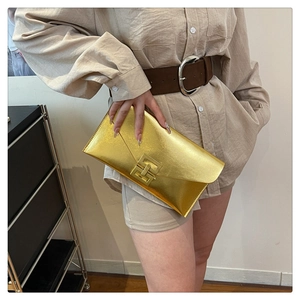 Close-up of golden envelope clutch with rectangular metal buckle in professional use