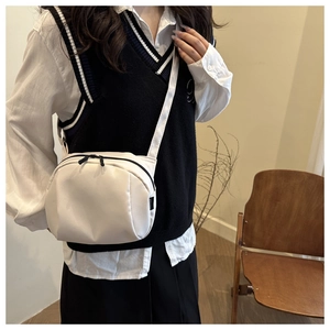 Detail of white nylon shell chest bag with black double zippers and wide strap