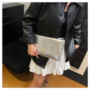 Détail d'un sac à main argenté métallisé avec boucle dorée rectangulaire et fine chaîne