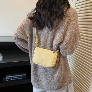 Schicke gelbe Crossbody-Tasche aus Leder mit Narbung kombiniert mit braunem Strickpullover