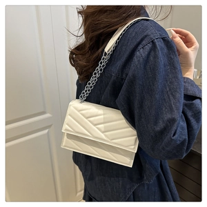 Gros plan d'un sac à bandoulière matelassé blanc avec chaîne argentée porté par un mannequin