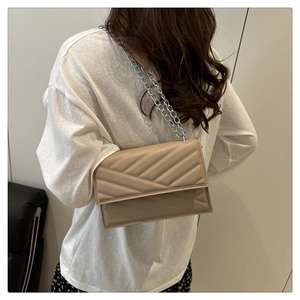Gros plan d'un sac à chaîne matelassé beige porté à l'épaule par un mannequin femme