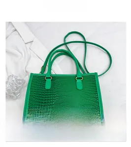 Dettaglio della trama a motivo coccodrillo su una borsa verde brillante con fibbie dorate
