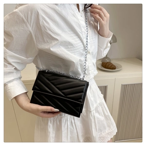 Détail du sac bandoulière noir matelassé avec chevrons et bandoulière chaîne argent