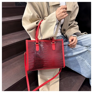Dettaglio della borsa tote rossa con stampa coccodrillo abbinata a un trench beige