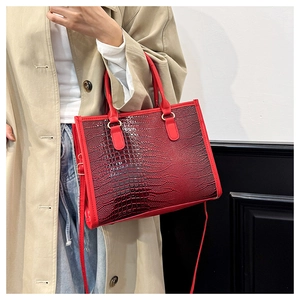 Dettaglio borsa tote rossa con texture coccodrillo, finiture dorate e tracolla lunga