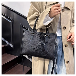 Vista dettagliata della borsa tote nera con motivo a coccodrillo indossata da una modella
